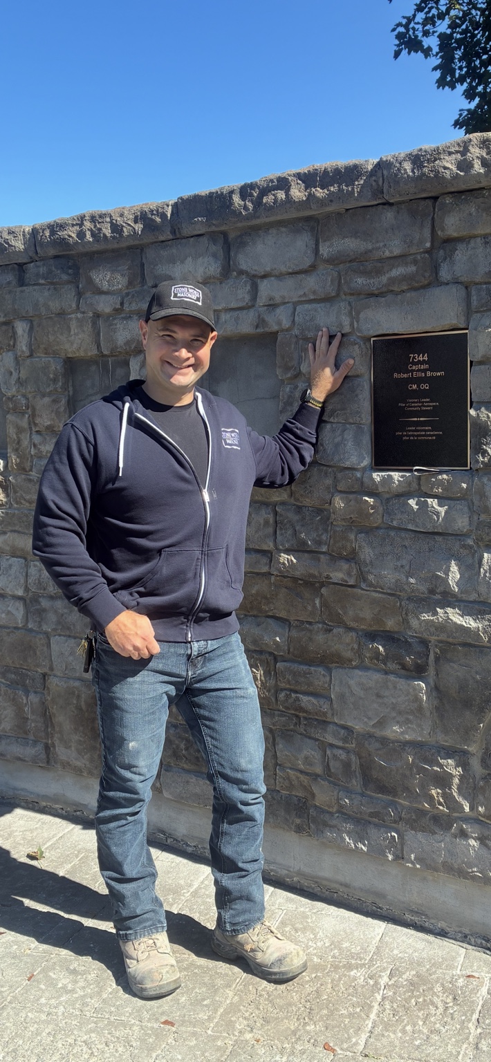 Stone Worx founder and lead mason Lee Rankin beside a commemorative plaque at the RMC Wall of Honor
